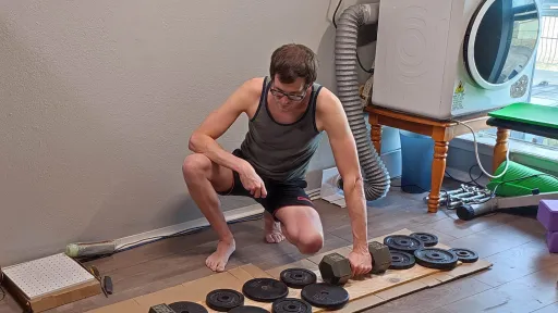 Curtis putting weights down on a long wooden board to glue together cardboard.